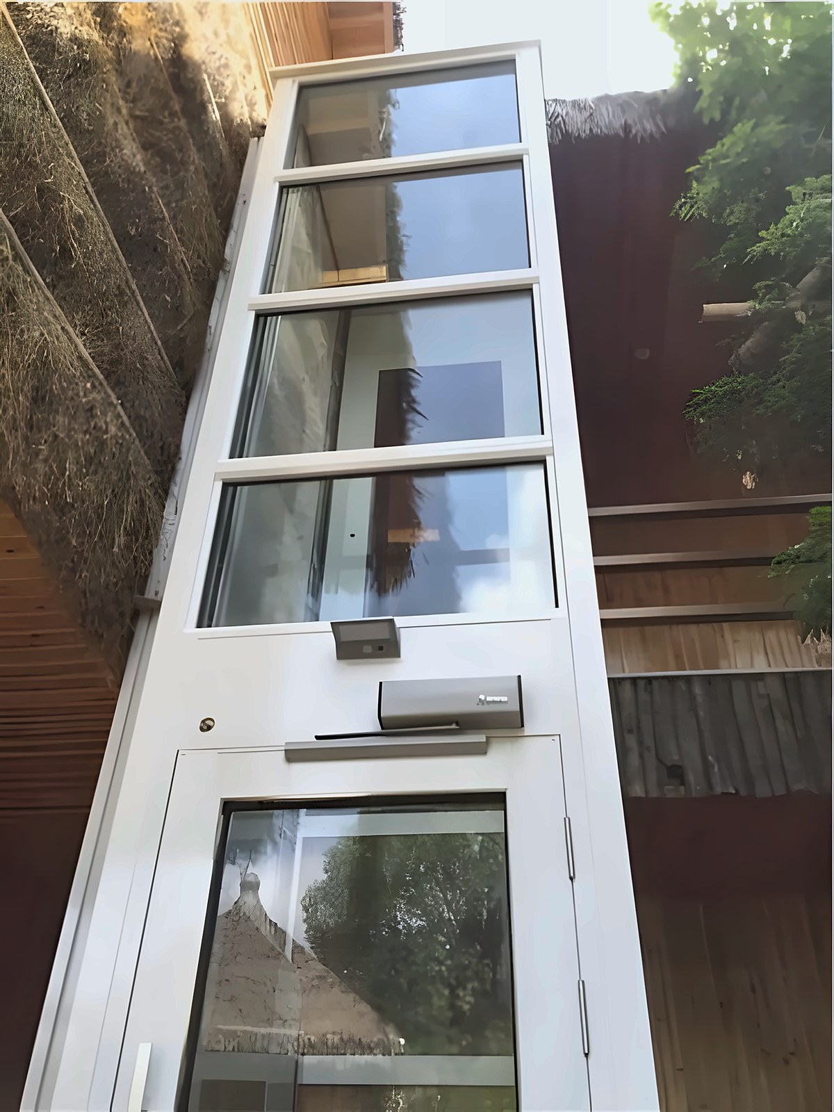 Outdoor home lift with a glass shaft on the garden side