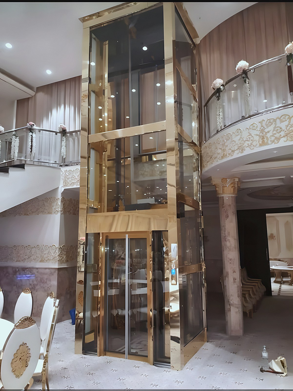 Glass lift with a gold frame in a villa hall